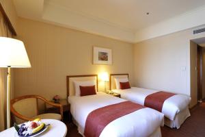 台北Hotel Riverview Taipei的酒店客房设有两张床和一张桌子。