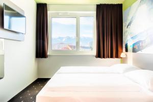 菲拉赫B&B Hotel Villach的酒店客房设有两张床和窗户。