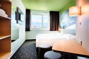 菲拉赫B&B Hotel Villach的酒店客房设有两张床和一张桌子。