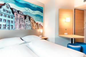 罗斯托克B&B Hotel Rostock City-West的卧室配有一张床,墙上挂有绘画作品