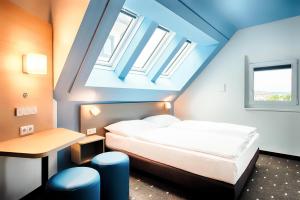 维也纳B&B Hotel Wien-Meidling的卧室配有床、桌子和窗户。