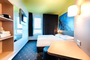 埃滕海姆B&B Hotel Rust-Ettenheim的酒店客房设有两张床和一张桌子。
