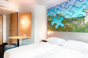 拉芬斯堡B&B Hotel Ravensburg的一间卧室设有两张床,墙上有拼图