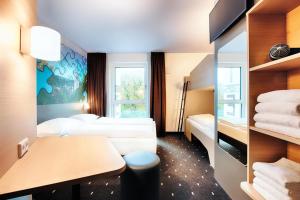 拉芬斯堡B&B Hotel Ravensburg的酒店客房配有两张床和一张书桌