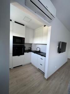 伊拉华Apartament nad Iławką的白色的厨房配有白色橱柜和黑色家电