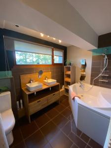 康村La villa dans les pins的一间带两个盥洗盆、浴缸和卫生间的浴室