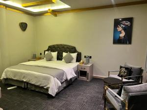 沙迦Daraysh Hotel的一间卧室配有一张大床和一把椅子