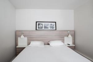 圣莫里斯基里亚德巴黎伊斯特酒店 - 文森森林的一间卧室配有一张带两盏灯的大型白色床。