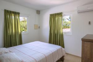 拉贡Whitehouse Lagun Apartments的一间卧室设有床铺和一个带绿色窗帘的窗户。