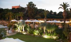 阿格里真托德拉瓦莱酒店的一个带遮阳伞和棕榈树的花园的度假村
