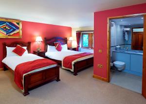 皇家滕布里奇韦尔斯卡姆登阿姆斯酒店的一间卧室设有两张床和红色的墙壁