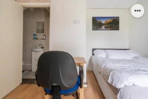 查塔姆Medway luxury Retreat free parking free wi-fi的一间卧室配有一张桌子和一张椅子,位于床边
