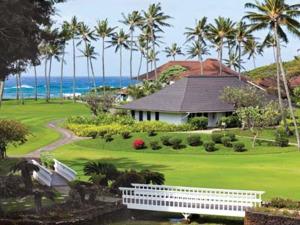 科洛阿Kiahuna Plantation Resort Kauai by OUTRIGGER的棕榈树和大海的高尔夫球场度假屋