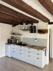 卡尔斯堡Svanen B&B的厨房配有白色橱柜和木制天花板