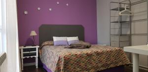 阿尔卡拉德荷那利斯Casa de Huéspedes con encanto El Sueño del Quijote的一间卧室设有紫色的墙壁和一张带毯子的床