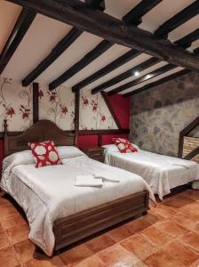埃尔瓦Apartamentos Rurales Fuente Chiquita的一间卧室配有两张带红色枕头的床
