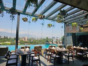 加德满都Hotel Barahi Kathmandu的一间带桌椅的餐厅和一个游泳池