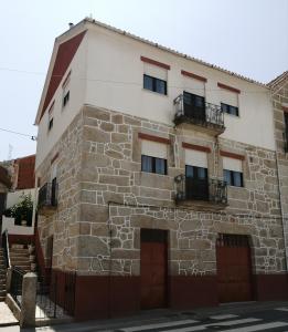 塔布阿苏Casa do César Douro Guest House的一座古老的石头建筑,设有两扇门和两个阳台