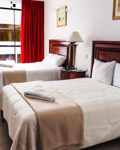 伊察Mc Hotel Ica的配有红色窗帘的酒店客房内的两张床