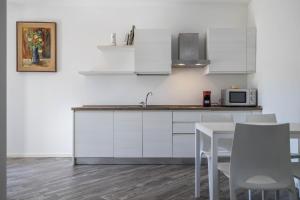 德罗Appartamenti Gaggiolo 1的厨房配有白色橱柜和桌椅