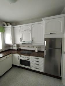 拉赫Piso Sol的厨房配有白色橱柜和不锈钢冰箱