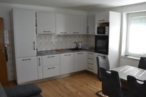 卢斯Apartma ob potoku的厨房配有白色橱柜和桌椅