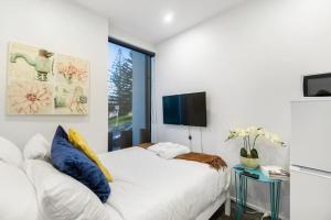 奥克兰Gorgeous Studio - Heart of Avondale - Netflix WiFi的一间白色卧室,配有床和电视