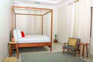 Kiembi SamakiKwale Residence的一间卧室配有一张天蓬床和一把椅子