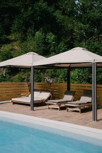 伊德里亚Chalet HerMes arT的游泳池畔的两把椅子和遮阳伞