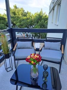 萨利Bella Luxury Apartment的阳台配有两张沙发和一张花瓶桌子