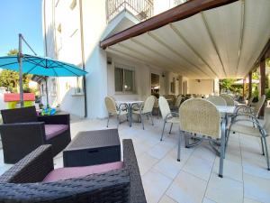 切塞纳蒂科Hotel Sasselli的庭院配有桌椅和遮阳伞。