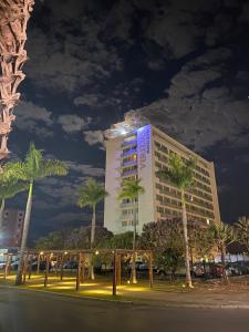 塞蒂拉瓜斯San Diego Suites Veredas Sete Lagoas的一座高大的建筑,前面有棕榈树