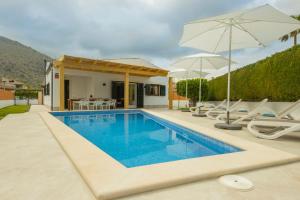 阿尔库迪亚Alcudia Beach House的房屋旁的游泳池配有椅子和遮阳伞