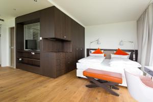 罗伊特林根阿卡尔姆酒店的一间卧室配有带橙色枕头的床和电视。