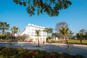 乌代浦乌代布尔宫殿丽笙度假村酒店的一座白色的大建筑,前面有棕榈树