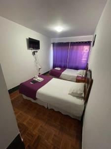 安托法加斯塔Zigal hotel的一间卧室设有两张床和一个带紫色窗帘的窗户。