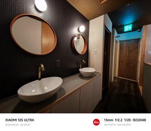 名古屋2023年6月開業 サカエ ゲストハウス的浴室设有两个水槽和两面墙上的镜子