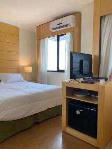 圣保罗Hotel Aeroporto Congonhas的一间卧室配有一张床和一张书桌上的电视