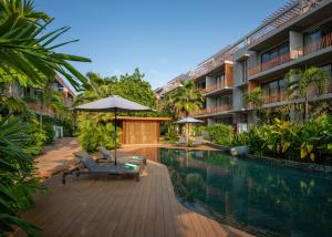 暹粒Angkor Grace Residence & Wellness Resort的一座带椅子和遮阳伞的游泳池位于大楼旁