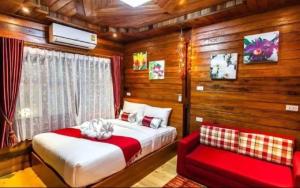 Ban Chong PhliAreeya phubeach resort wooden house的一间卧室配有一张床和一张红色的沙发