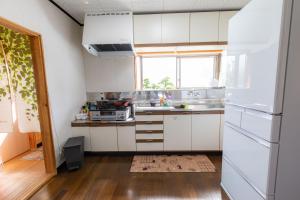 五岛Goto I-House的厨房配有白色橱柜和窗户。