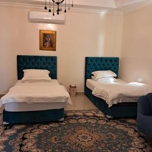 阿布扎比Sara Farm的卧室设有两张床铺,配有蓝色床头板