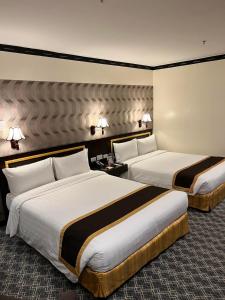 马尼拉Bayview Park Hotel Manila的酒店客房设有两张床和两盏灯。