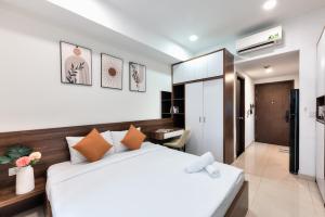 胡志明市January Apartment的卧室配有带橙色枕头的大型白色床