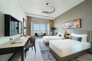 迪拜DAMAC Hills 2 Hotel, an Edge by Rotana Hotel的酒店客房配有两张床和一张书桌