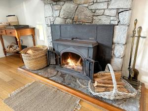 FalmouthWhite Shell Cottage - Woodfire & Beachfront的带壁炉的客厅内的石头壁炉