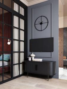 华沙Luxury Touch Apartment by ECRU WWA26的客厅配有电视和墙上的时钟