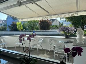 罗拉赫Burghotel Lörrach的庭院配有椅子和一张带紫色花卉的桌子