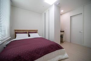 大田Comma的一间卧室配有一张带紫色毯子的大床