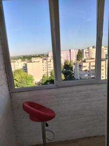 卢茨克Однокімнатна квартира Olympya біля парку Героїв Майдану的坐在窗前的红色凳子
